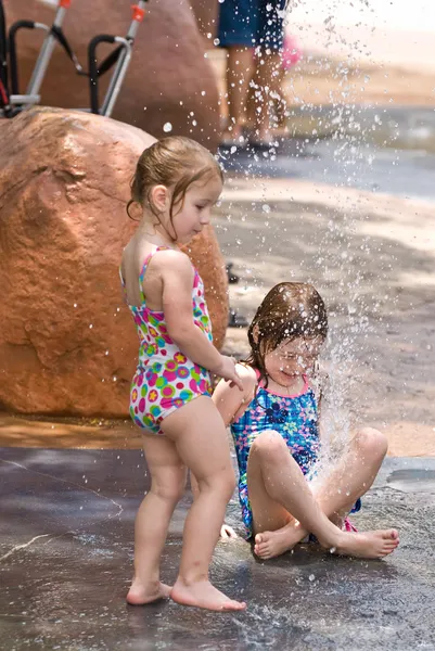 Two young sisters playing together in water