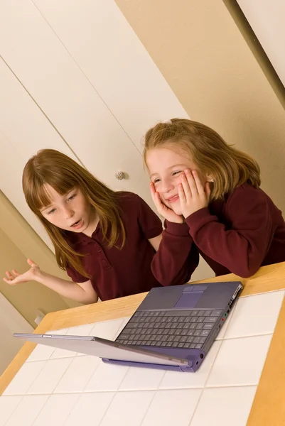 Two young girls working on a laptop computer