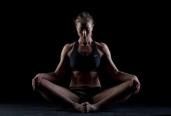 One caucasian woman exercising yoga meditating in silhouette studio on black background