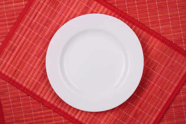 White empty plate on a red