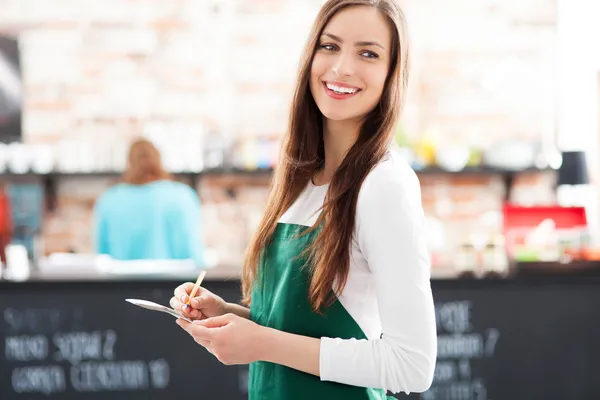 Young waitress holding notepad in cafe