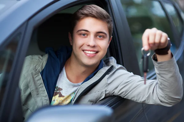 Young man sitting in car holding car keys