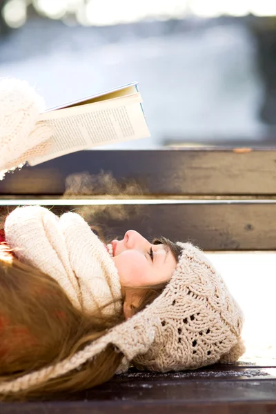 Woman reading book outdoors at winter time