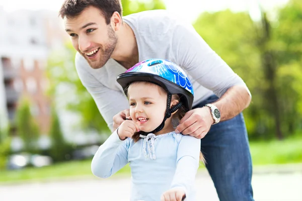 Father helping daughter with helmet