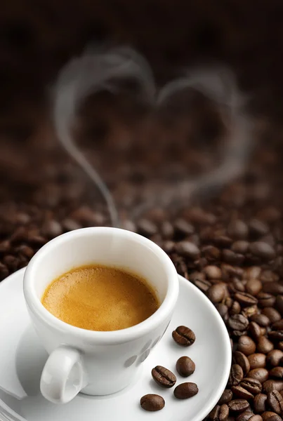 Coffee cup with heart- shaped steam on background of coffee beans