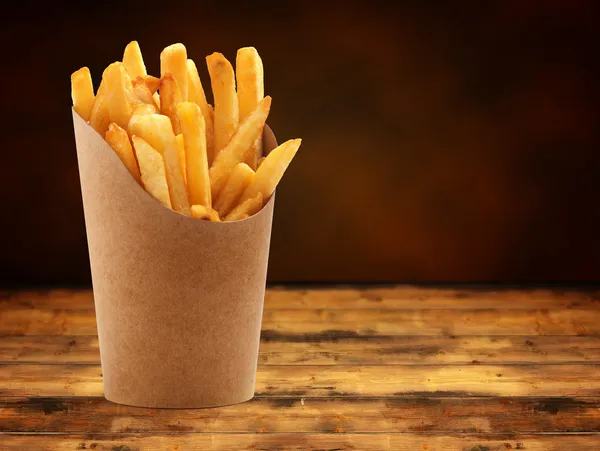 French fries in a paper basket on wooden table