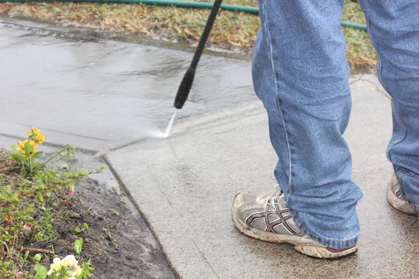 Man cleaning footpath with water pressure cleaner
