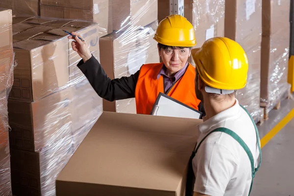 Manager giving worker instruction in warehouse