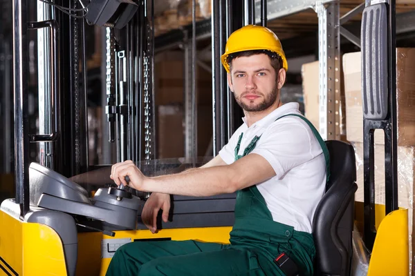 Storehouse employee driving on forklift