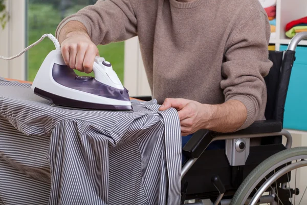 Disabled man ironing shirt