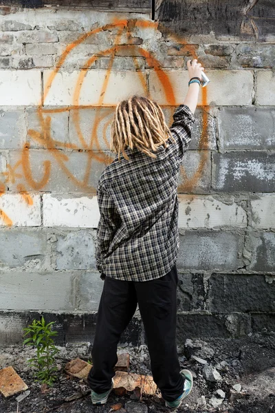 Hooligan painting graffiti on the building
