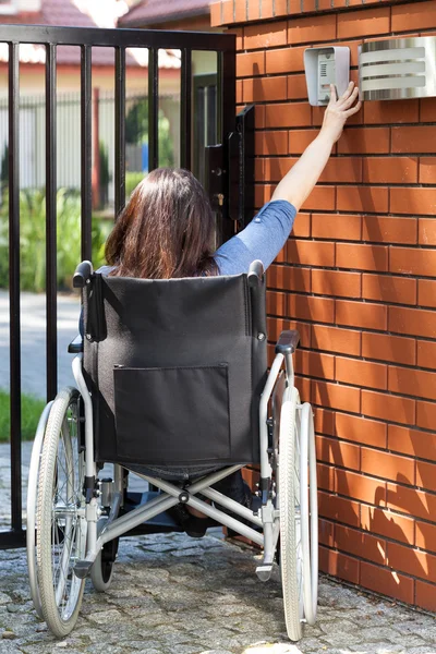 Woman on wheelchair dialing intercom