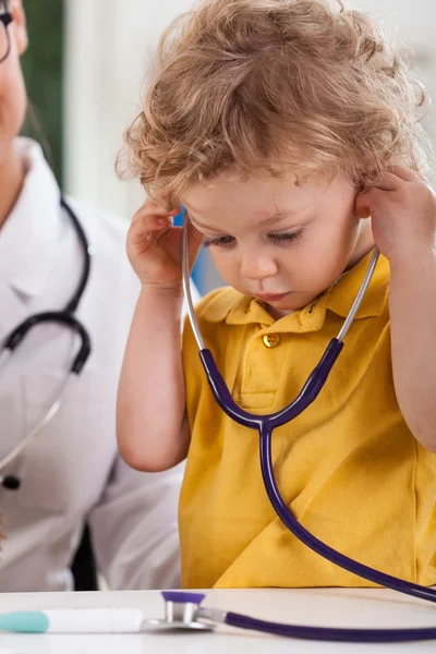 Boy with curly blond hair playing with stethoscope