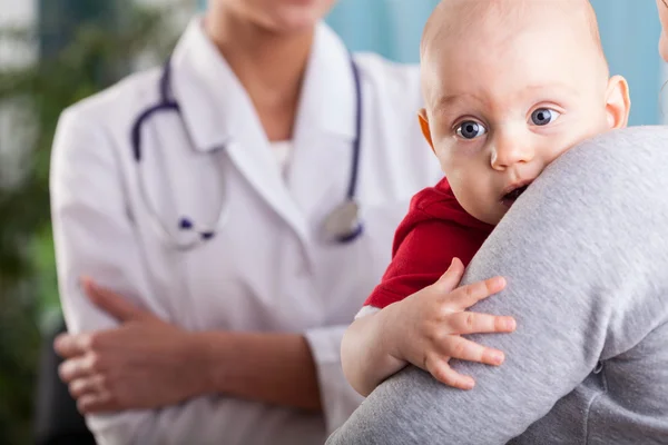 Baby boy in the arms of mother at doctor\'s office