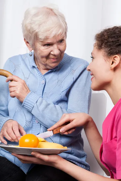 Nurse and elderly woman eating fruits