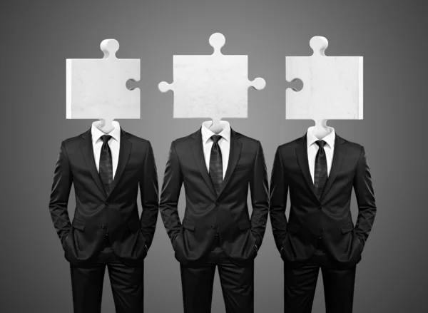 Team of businessman with puzzle pieces instead heads