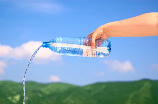 Hand holding bottle with pure water on mountain background