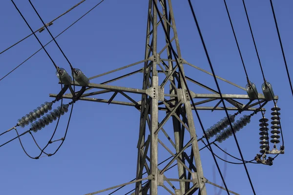 High voltage transmission pylon on blue sky background