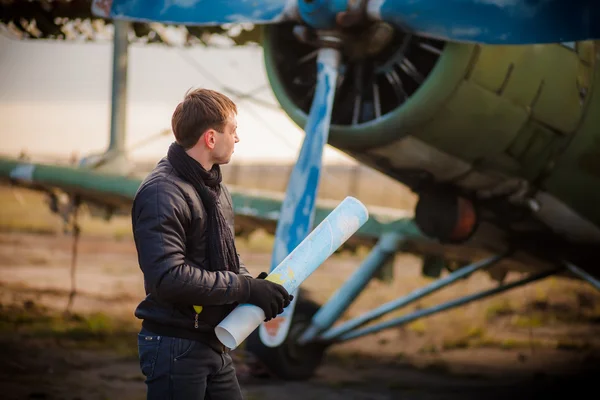 Man staying with map near retro airplane