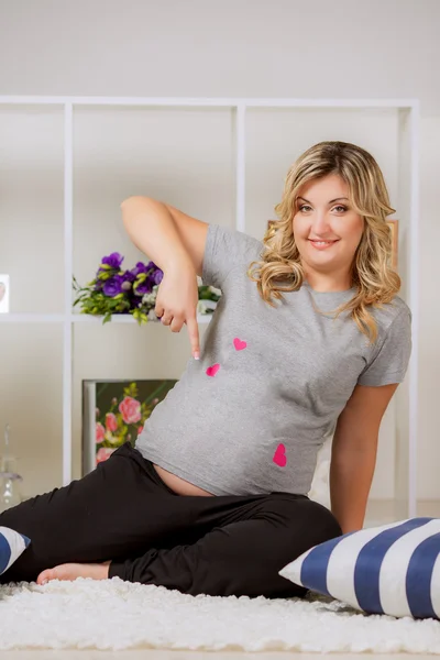 Pregnant woman points a finger at the stomach