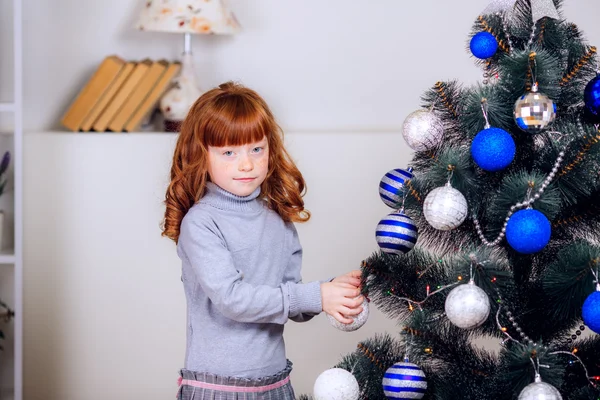 Girl hangs on the Christmas tree toys