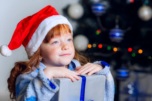 Little girl in Christmas hat with a New Year gift