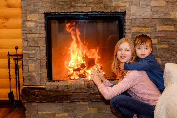 Brother and sister hugging near the fireplace