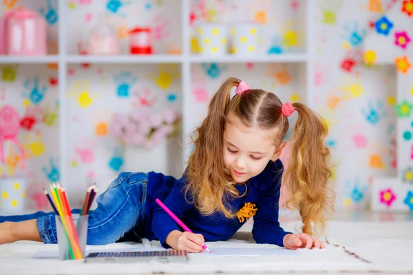 Happy little girl draws with colored pencils
