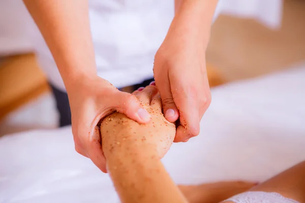 Cosmetologist applies body scrub