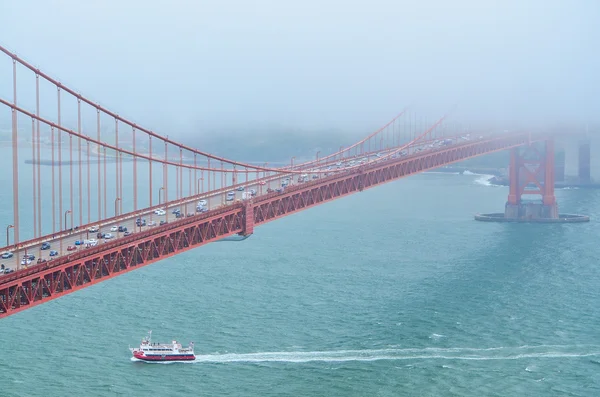 Closeup view of Golden Gate Bridge from Marin Headlands with a boat passing underneath in San Francisco, California