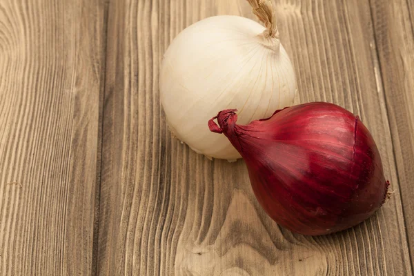 Fresh raw red and white onions on a wooden table with copyspace.