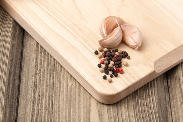 Fresh garlic and pepper on wooden table and wooden cutting board