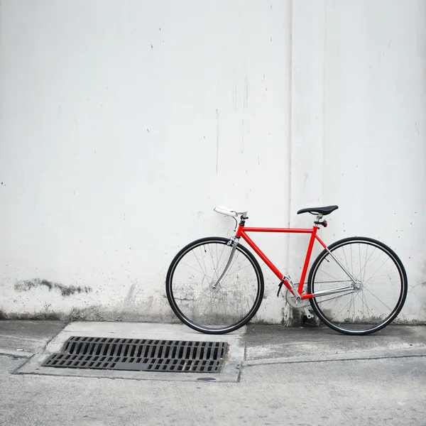 Modern red bicycle leaning on white wall