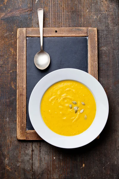 Pumpkin soup in white plate on vintage slate chalk board