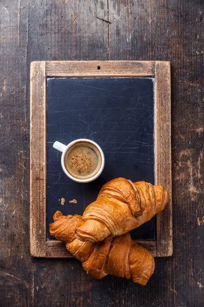 Coffee cup and croissants on vintage slate chalk board