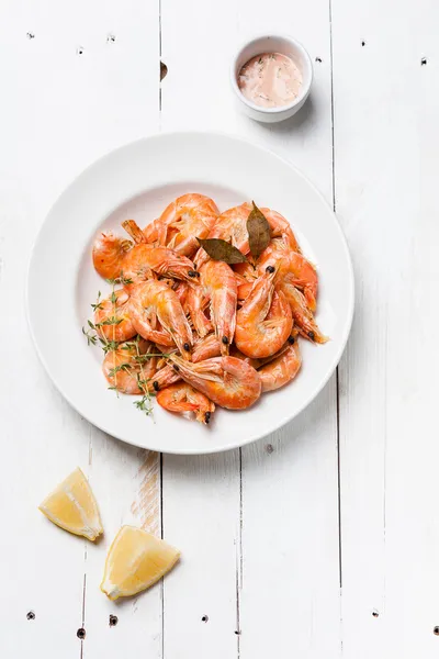 Prepared shrimps on white plate on white wooden background