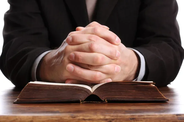 Praying hands on an open bible