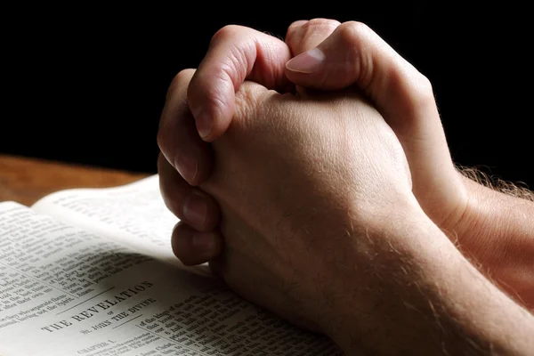Praying hands on an open Bible