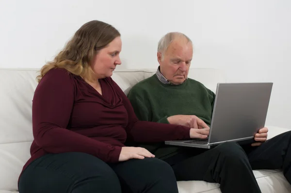 Young woman on laptop and pensioners