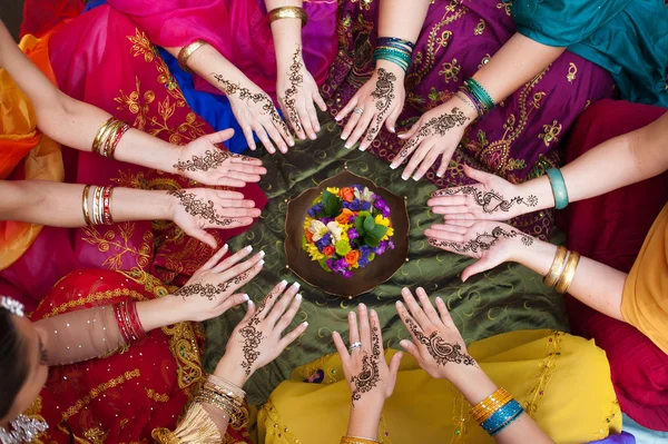 Six pairs of henna decorated female hands arranged in a circle