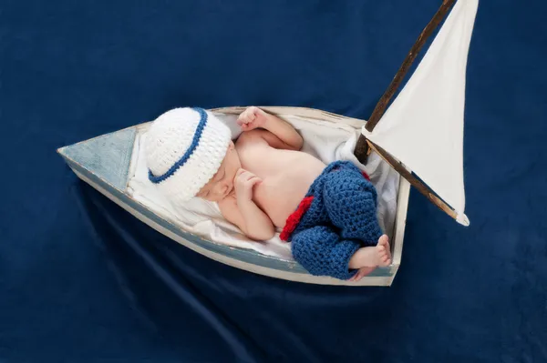 One week old newborn baby boy wearing a white and blue sailor hat.