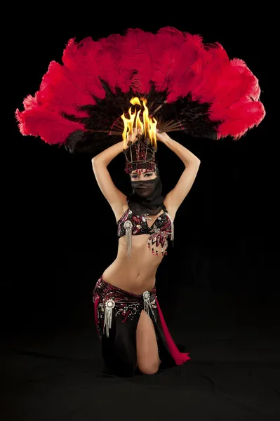 Exotic belly dancer wearing a red and black costume with hijab and fire headdress.