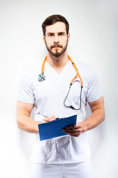 Handsome doctor standing next to wall