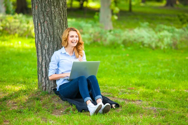 Beautiful woman sitting in park with laptop