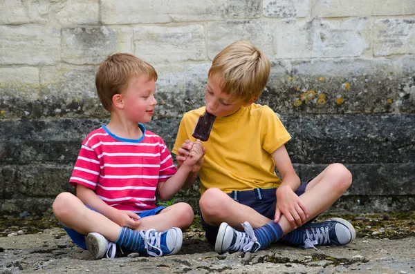 Two boys sharing an ice lolly