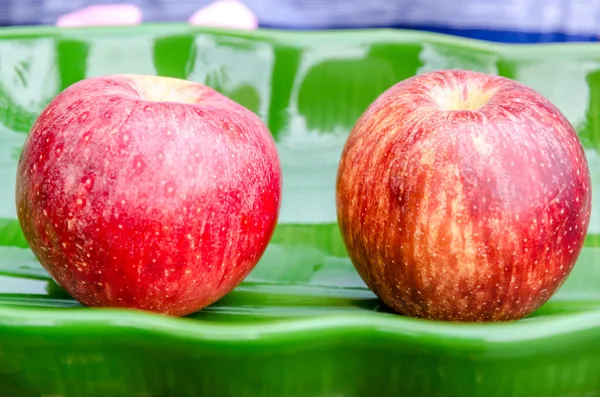 Two apples placed on the green dish