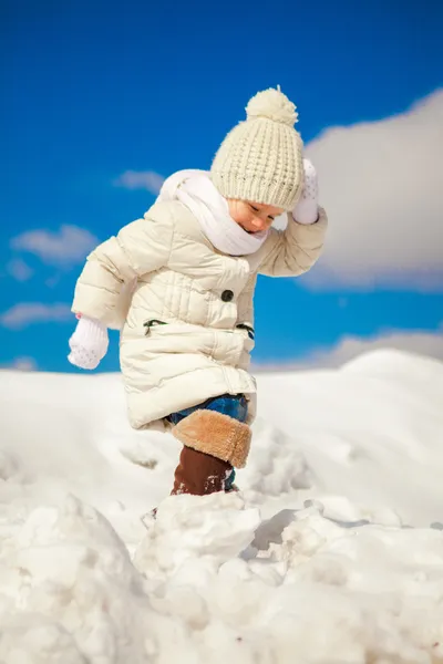 Little happy girl is walking in the snow on a sunny winter day