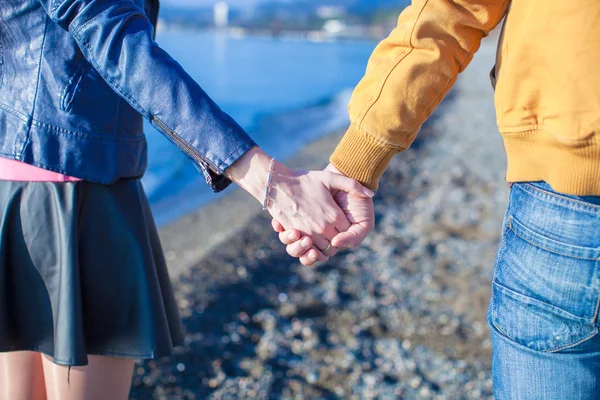 Rear view of a man and woman holding hands on the sea background