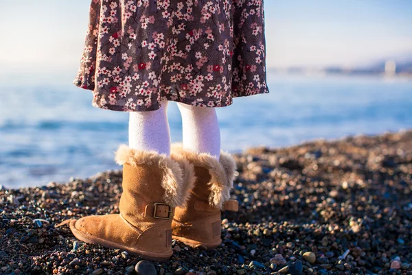 Closeup of legs little girl in cozy fur boots background the sea