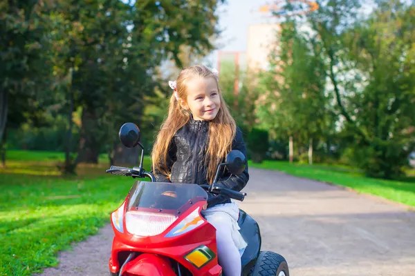 Portrait of little adorable rock girl in leather jacket sitting on her bike